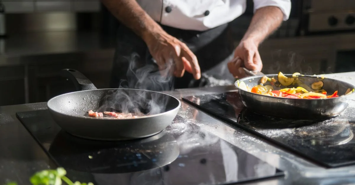 Un chef prépare habilement un repas avec des ingrédients frais sur une cuisinière électrique, mettant en avant son expertise culinaire.